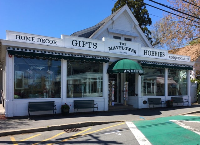 A white storefront labeled "The Mayflower" featuring home decor, gifts, and hobbies on Main Street.